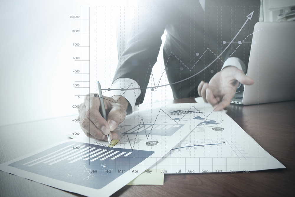 close up of businessman hand working on laptop computer with business graph information diagram on wooden desk as concept-1